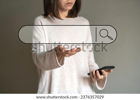 The girl holds a phone in her hand, searches for information on the Internet through the search bar, develops her business online, a search sign is added, a magnifying glass.