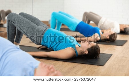 People of different ages performing glute bridge during group Pilates workout. Active lifestyle and wellness concept Royalty-Free Stock Photo #2376372047