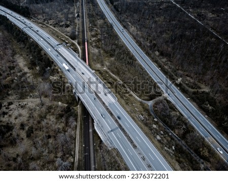 An aerial shot of multiple cars traveling on a highway through a scenic valley in Germany.