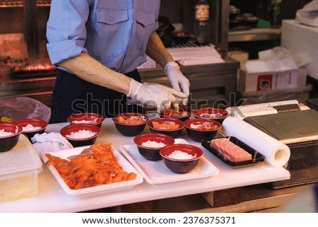 picture of an unrecognizable chef at a street kitchen in the fish market in Tokyo prepares bowls of food