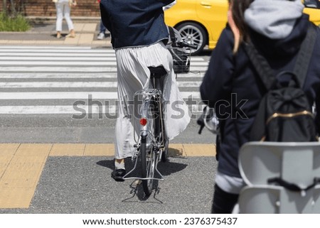 picture of a woman waiting on a bicycle in front of the pedestrian crossing