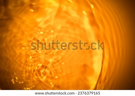 Picture of the surface of the water rippled with orange rays, glittering lights, and air bubbles.