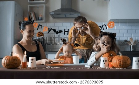Family of four having fun while preparing for Halloween party in the kitchen