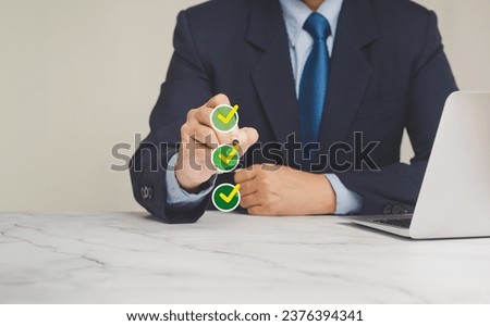 Checklist concept. A Businessman in a suit uses a pen to tick the correct sign in the checkbox for the quality document control checklist and business approval project concept.