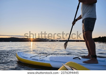Male legs on a paddle board. Royalty-Free Stock Photo #2376394445
