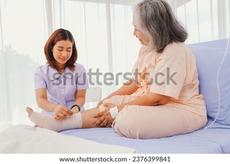 Female nurse care elderly female patient hospitalized patient with ankle pain from sprained foot Nurse uses bandage relieve pain  makes patients feel good and encourages them to recover from illness.