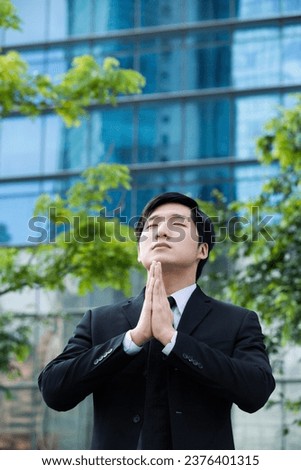 Coneptual image of an Asian Businessman praying for success 