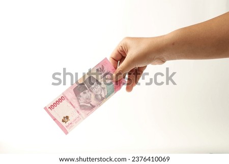 Hand holds Indonesian currency cash. Indonesian Money. IDR 100000. Raw Photo material.