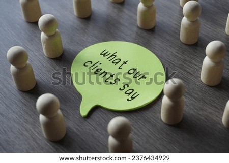 A group of wooden figurines surrounding a speech bubble with text WHAT OUR CLIENTS SAY. Business, feedback concept Royalty-Free Stock Photo #2376434929