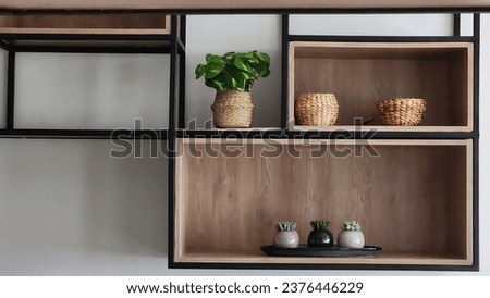 a simple wooden hanging shelf with black iron frame, minimalist decoration and some small plants Royalty-Free Stock Photo #2376446229
