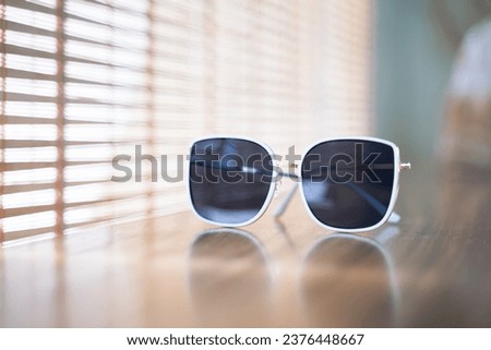White rimmed sunglasses on the table. Bokeh light background in the morning.