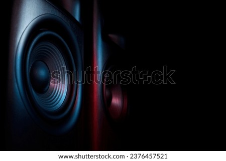 Modern sound speakers in neon light on black background, closeup. Space for text Royalty-Free Stock Photo #2376457521