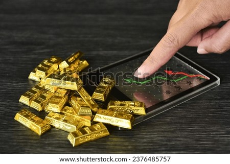 Gold bar on calculator with trading line graph for calulate the gold price. Gold is hard commodity , risk asset, tangible value that used to be gold reserve, save assets during war and economic crisis Royalty-Free Stock Photo #2376485757