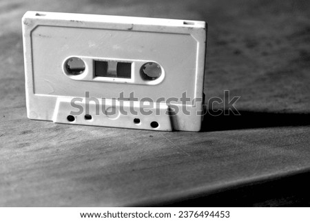 Monochrome old audio cassette on a wooden table.