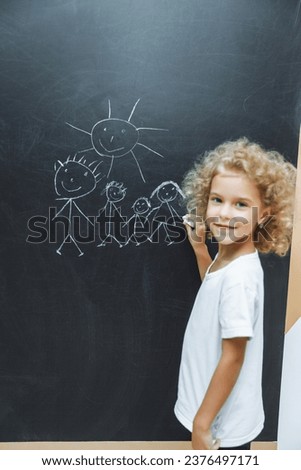 Little girl draws a family on a chalkboard