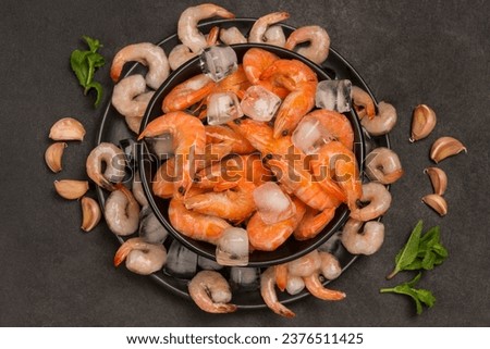 Tiger prawns and shrimp in black plate with ice. Black background. Healthy diet nutrition. Flat view
