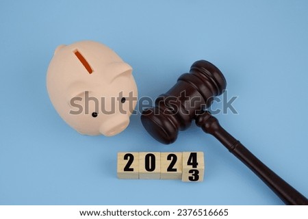Piggy bank, gavel and wooden cubes with numbers 2023 and 2024. Laws and invest funds in year 2024.