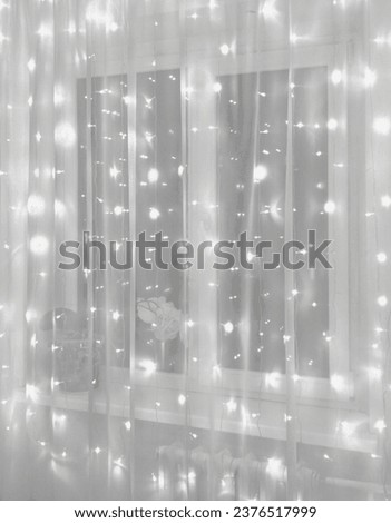 In the room, white tulle hangs on the window, behind which a Christmas garland shimmers