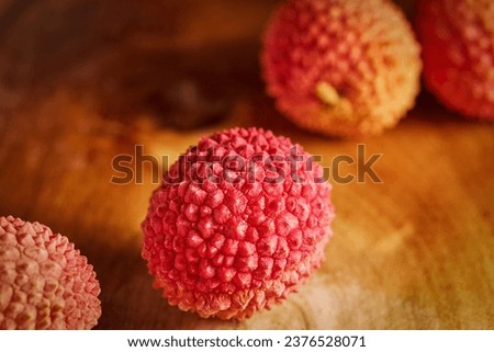 a group of ripe lychees , an exotic fruit , photographed close-up on a wooden tabletop , macro photography , a very tasty and healthy berry ,vitamin concept
