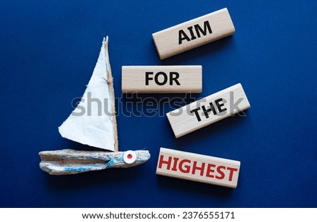 Aim for the Highest symbol. Concept words Aim for the Highest on wooden blocks. Beautiful deep blue background with boat. Business and Aim for the Highest concept. Copy space.