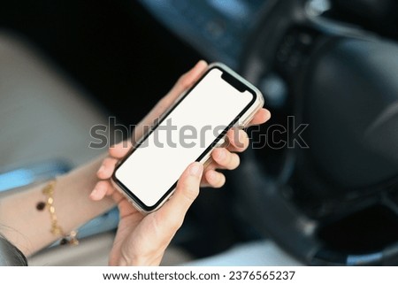 Young woman using mobile phone while driving car for navigation or searching destination on gps map
