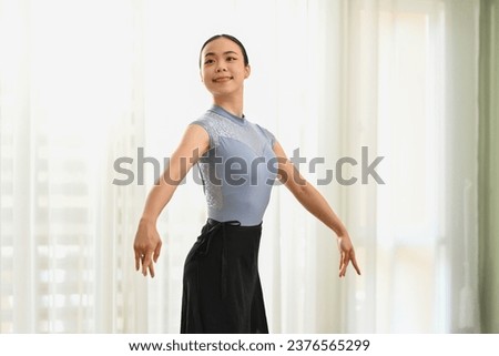 Charming young woman practicing ballet in dance studio