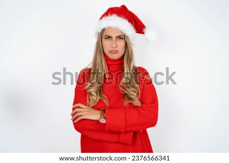Gloomy dissatisfied Young beautiful woman looks with miserable expression at camera from under forehead, makes unhappy grimace