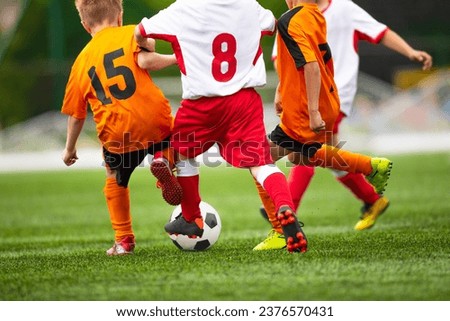Young boys playing football game on a school tournament. Football soccer match for children. Dynamic, action picture of kids competition during playing football