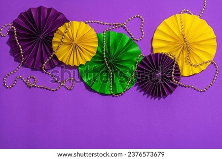 Festive Mardi Gras masquerade purple background. Fat Tuesday carnival, beads, traditional decor. Symbolic colors, trendy hard light, dark shadow, flat lay, top view