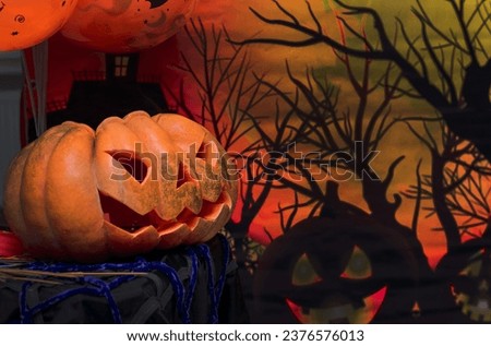 An orange pumpkin stands on a stand in the room. Festively decorated pumpkin for Halloween. Autumn bright composition against the background of a banner and balloons.
