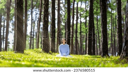 Woman relaxingly practicing meditation in pine forest to attain happiness from inner peace wisdom with beam of sun light for healthy mind and soul for healthy mind and soul Royalty-Free Stock Photo #2376580515