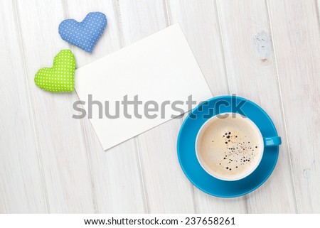 Valentines day toy heart, blank greeting card and coffee cup over wooden table background