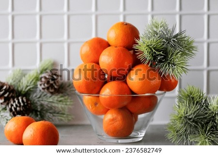 Bright orange tangerines in a glass vase on a gray table. Christmas and New Year concept. Horizontal. Soft focus.
