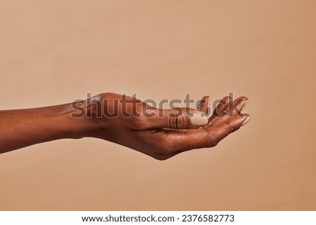 Close up of african american woman hand with palm facing upwards isolated on brown background. Female black hand showing empty hand. African girl holding your beauty product. Royalty-Free Stock Photo #2376582773