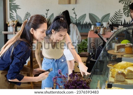 Confident beautiful woman customer ordering cake with owner at coffee shop, chooses cake for take away, small business owner recommend regular customer buy bakery in morning for breakfast.  