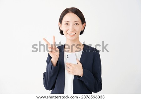 Asian middle aged businesswoman with the smartphone peace sign gesture in white background
