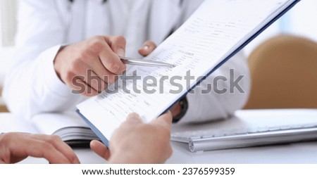 Male doctor hand hold silver pen and showing pad. Physical agreement form signature disease prevention ward round reception consent contract sign prescribe remedy healthy lifestyle concept Royalty-Free Stock Photo #2376599359