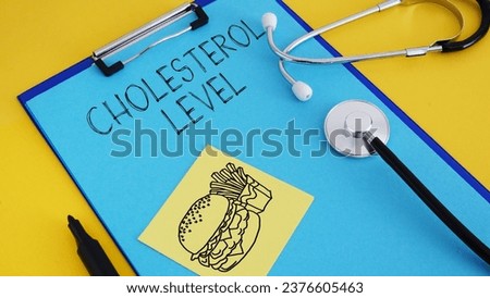 Cholesterol level is shown using a text and picture of fatty food Royalty-Free Stock Photo #2376605463