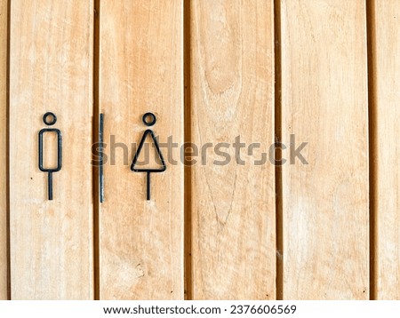 Toilet symbol: male and female with a wooden floor in the background.