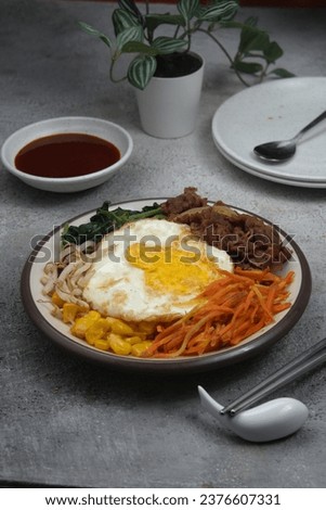 Bibimbap. Sometimes romanized as bi bim bap or bi bim bop, is a Korean rice dish. The term bibim means mixing and bap is cooked rice. It is served as a bowl of warm white rice topped with namul 
