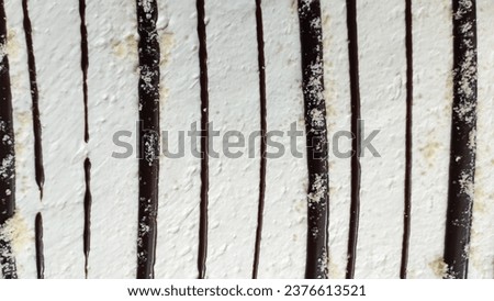 Sweet background with chocolate lines on white cream. High quality stock photo.