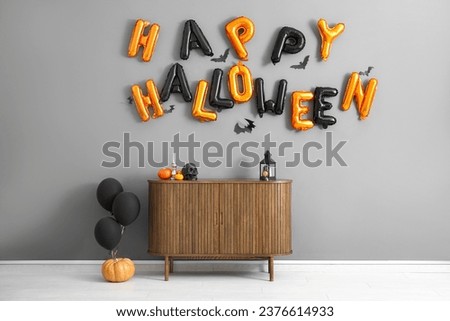 Text HAPPY HALLOWEEN made of balloons on grey wall in living room