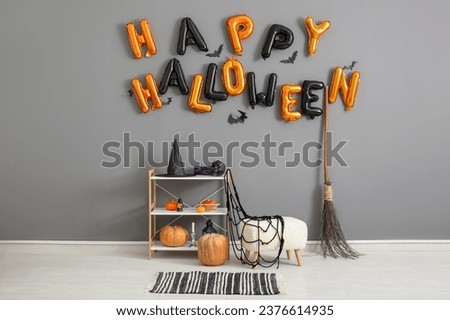 Shelving unit and text HAPPY HALLOWEEN made of balloons hanging on grey wall in living room