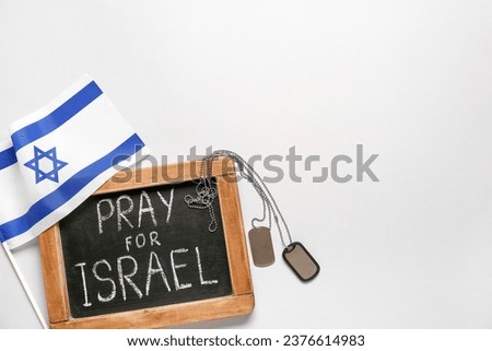 Chalkboard with text PRAY FOR ISRAEL, flag and dog tags on white background Royalty-Free Stock Photo #2376614983