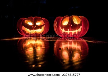 Two Halloween pumpkins with scary faces for party night. Close up picture of Halloween pumpkins with burning eyes.