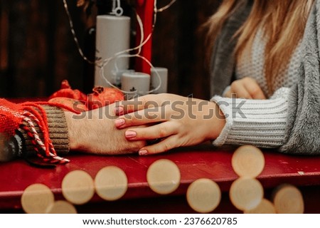  a couple in love on a date holding hands against the background of New Year's decor and with lights from the garland in the foreground