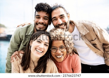 Group portrait of four multiracial united friends outdoors - Friendship concept with millennial guys and girls enjoying day out on city street - Focus on women face
