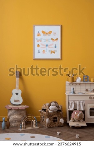 Cozy interior design of warm kids room interior with mock up poster frame, children kitchen, guitar, braided basket, plush monkey, yellow wall, round rug and personal accessories. Home decor. Template