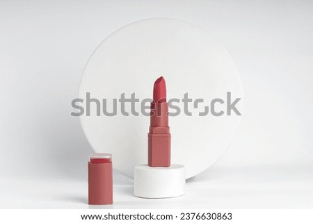A sample of red lipstick standing on a white podium presenting demonstration product