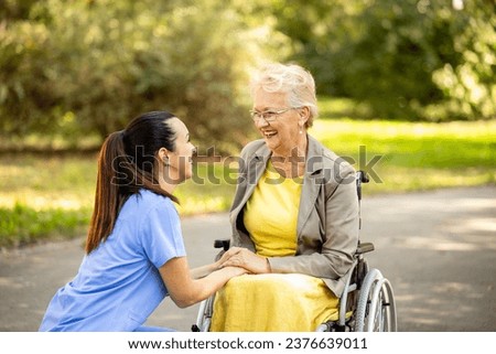 Nursery home concept. Good relations between nurse and elderly woman in wheelchair. Royalty-Free Stock Photo #2376639011